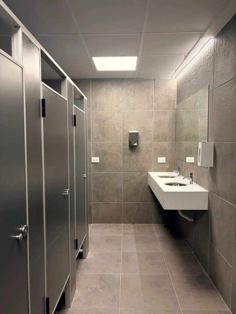 Baños de Conecta Pádel con tabiques sanitarios grises (foto 1 de 2)