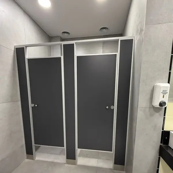 Baño de Milanga Co. con tabiques sanitarios oscuros